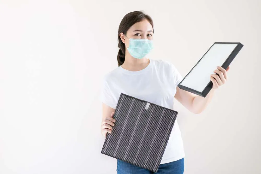 Woman holding a dirty air filter and a clean one.
