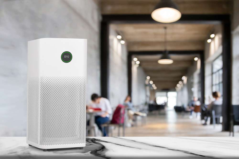 Air purifier sitting on counter with people in the background.
