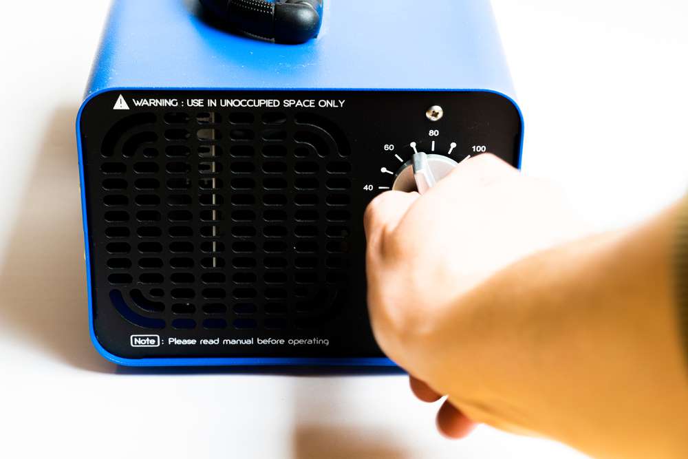 Closeup of someone's hand turning on an ozone generator.