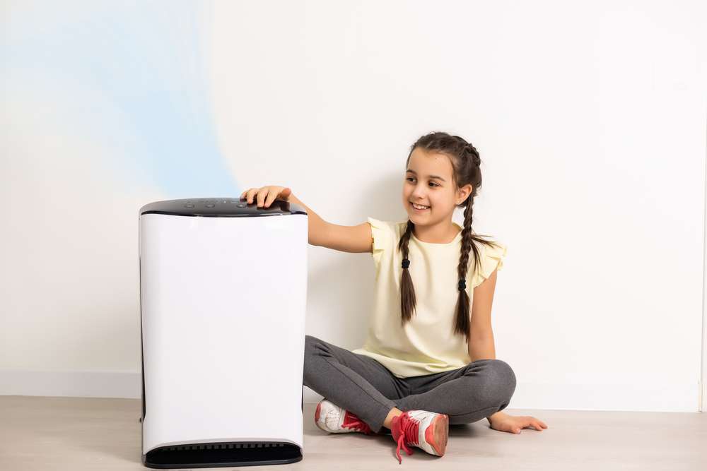 Girl pressing a button on an air purifier.