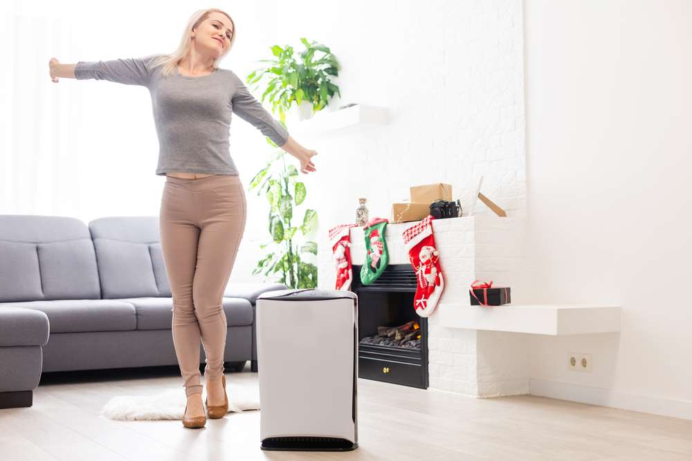 Woman stretching next to an air purifier in the living room.