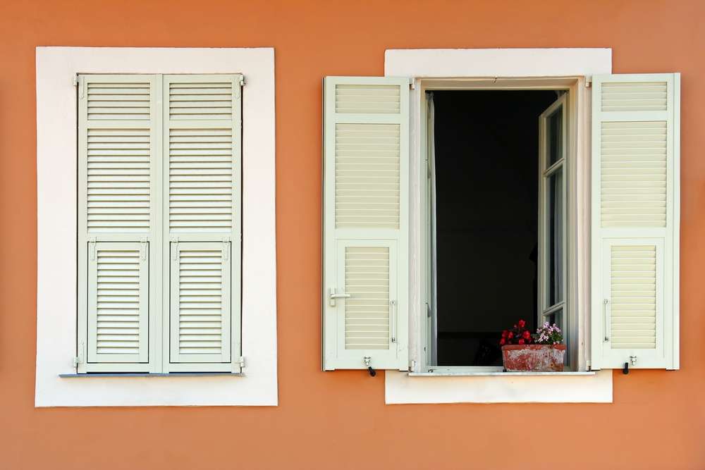 Exterior wall that's orange and has one open window and one closed window.