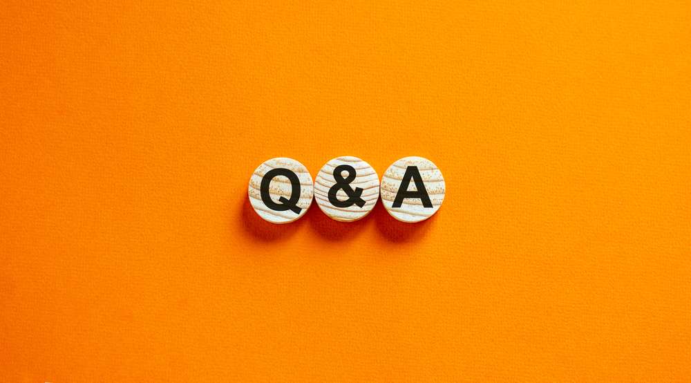 Wooden circles with the letters Q&A printed on them and sitting on an orange background.