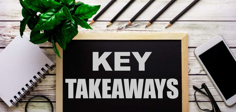 Black board sitting on a wooden table with the words, "Key Takeaways" written on it.