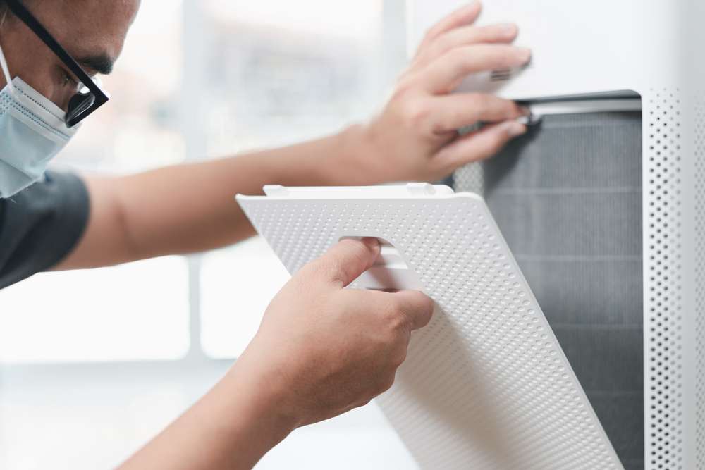 Man about to pull out a HEPA filter in an air purifier.