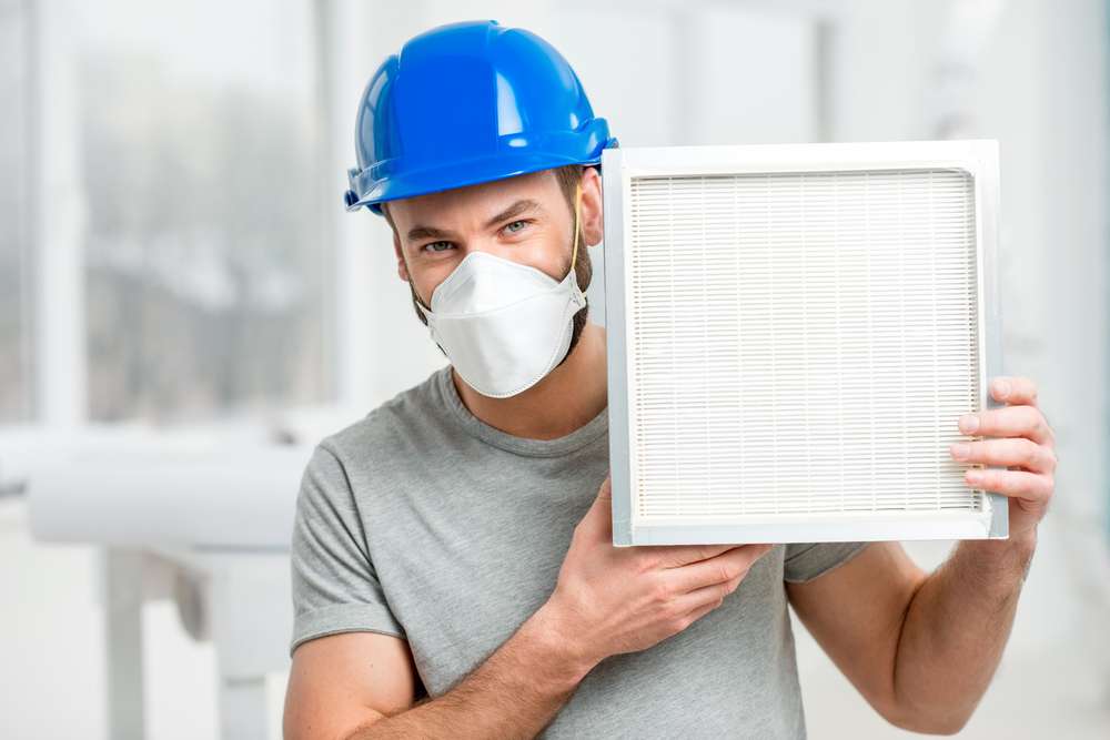 Construction worker holding a clean HEPA filter.